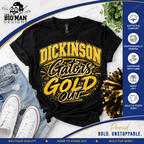 A black graphic T-shirt laid flat with distressed blue jeans, white sneakers, and a gold-and-black pom-pom accessory around it. The shirt has a large yellow and black 'DICKINSON Gators GOLD OUT' design.