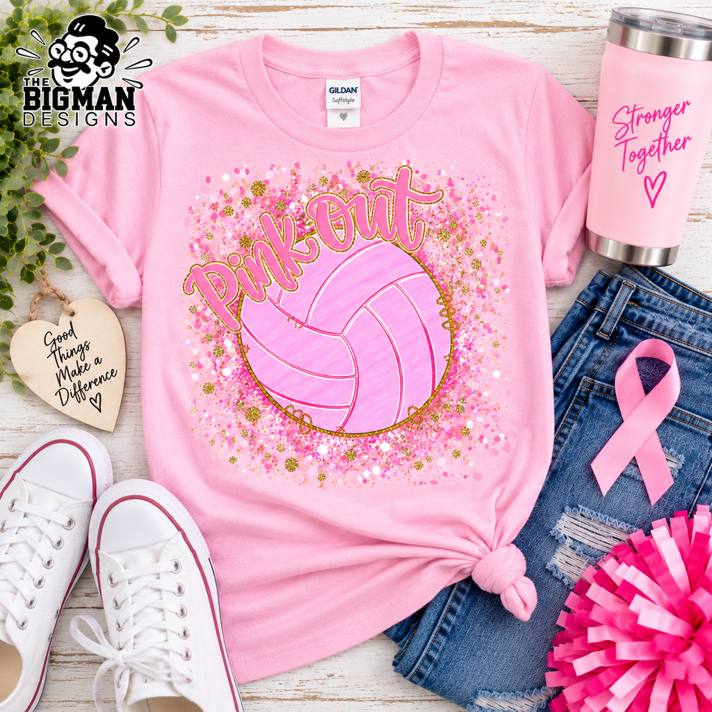 A pink short-sleeve T-shirt laid flat on a rustic white wood surface, styled with jeans, white sneakers, a pink tumbler, a pink ribbon, and decorative props. The shirt has a large volleyball graphic with the words 'Pink Out' surrounded by pink and gold glitter-style splatter.