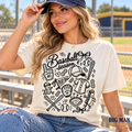 Woman wearing a natural-colored Baseball Season T-shirt with black baseball doodles and bows at a ballpark.