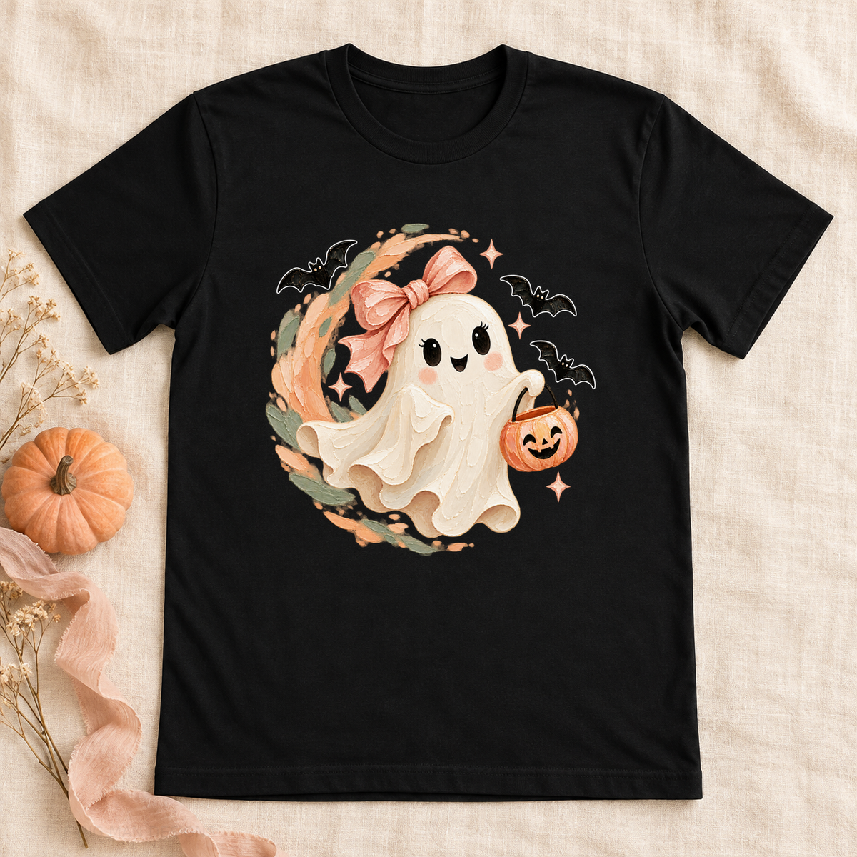 Black Halloween tee with a smiling ghost, blush bow, pumpkin pail, and white-outlined bats.