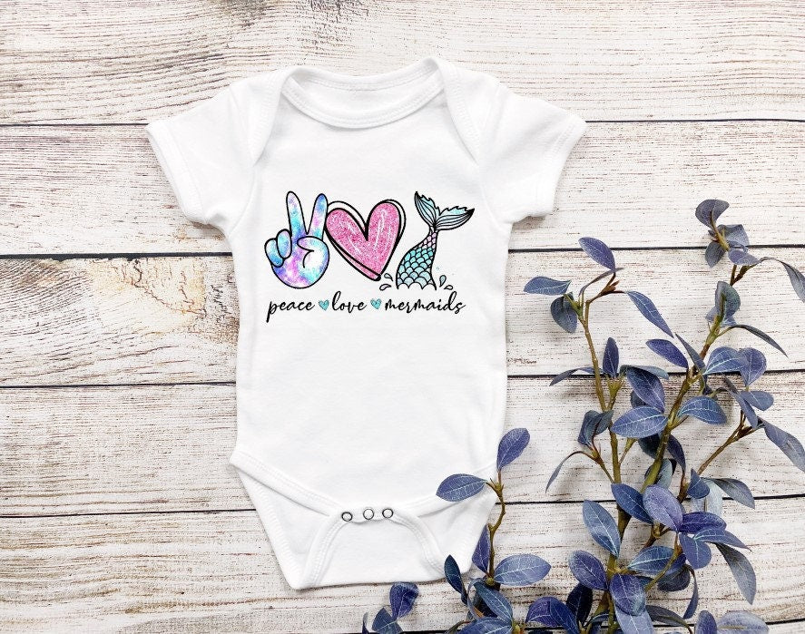 Bring the magic of the sea to your little one with our Peace Love Mermaid baby bodysuit or onesie! This adorable design is perfect for baby girls who love mermaids and all things magical. Whether you're celebrating a birthday or just looking for a cute outfit, this onesie is a must-have! Made from soft, 100% cotton Gerber brand onesies, it's designed for ultimate comfort. includes faux glitter