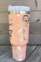 Pink large tumbler with handle laser engraved with hearts, the Betty Boop name and Betty Boop herself doing poses.