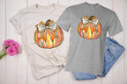 A cozy fall t-shirt featuring a brushstroke pumpkin with a faux glitter effect and a coquette bow. This trendy fall shirt is made from 100% cotton and available in sport grey, natural, black, and white. Perfect for a pumpkin patch outfit, Thanksgiving outfit, or a cute autumn aesthetic. The premium DTF print ensures durability with no cracking or peeling. A must-have for cottagecore and neutral fall fashion lovers! available on grey, black, white, and natural.