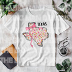 Show off your Texas pride with a feminine, coquette twist! This State Floral Coquette Texas DTF transfer features a beautifully hand-drawn Texas silhouette, adorned with delicate floral details and a soft, vintage-inspired aesthetic. Whether you're a proud Texan, a country girl at heart, or just love Southern charm, this design is perfect for rodeo season, boutique apparel, and everyday wear! on a white toddler shirt
