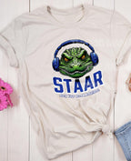 Get ready to rock testing season with this high-quality DTF transfer featuring a gator head wearing headphones and the phrase STAAR Rock Your Accommodations! Perfect for teachers, administrators, and school staff, this ready-to-press transfer makes it easy to create custom shirts for testing season! on natural