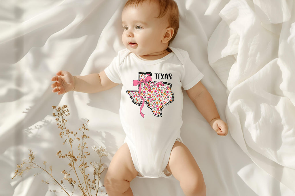 Dress your little one in Texas charm with a coquette twist! This adorable State Floral Coquette Texas design features a hand-drawn Texas silhouette adorned with delicate florals for a soft, vintage-inspired Western aesthetic. Whether for rodeo season, Texas pride, or everyday Southern style, this onesie or toddler tee is a perfect choice! Onesie