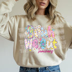 Woman wearing a natural-color crewneck sweatshirt with colorful “Bruh We Out Teachers” graphic, posing casually indoors.