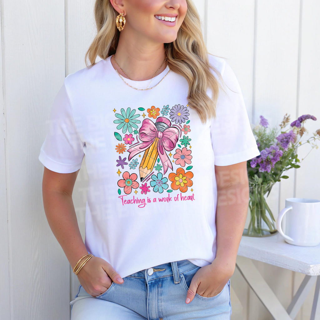 Woman smiling in white t-shirt showcasing vibrant "Teaching is a Work of Heart" pencil with flowers.