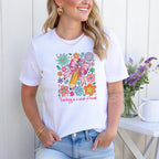 Woman smiling in white t-shirt showcasing vibrant "Teaching is a Work of Heart" pencil with flowers.