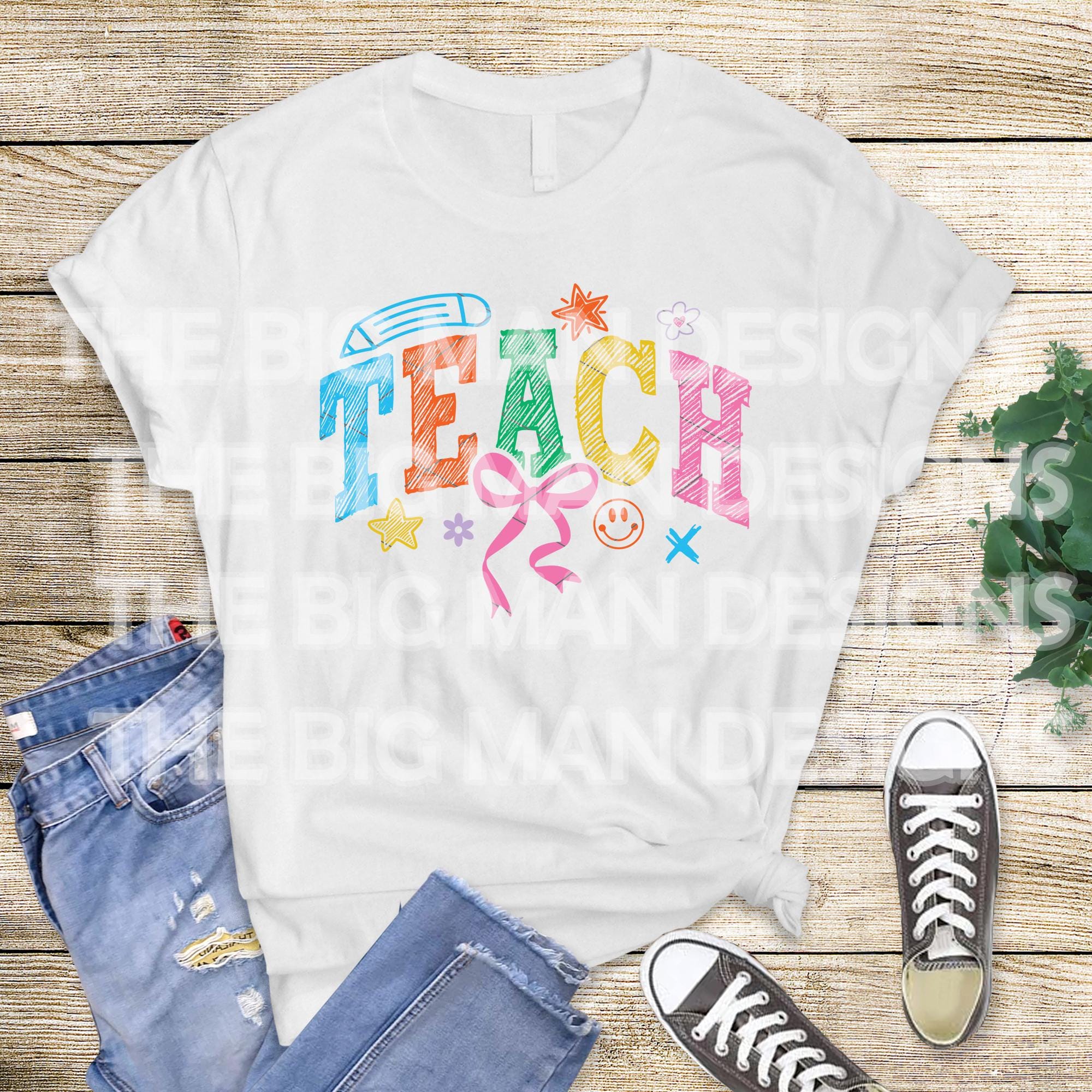 Flatlay of a white T-shirt with colorful "TEACH" design, paired with jeans and sneakers.