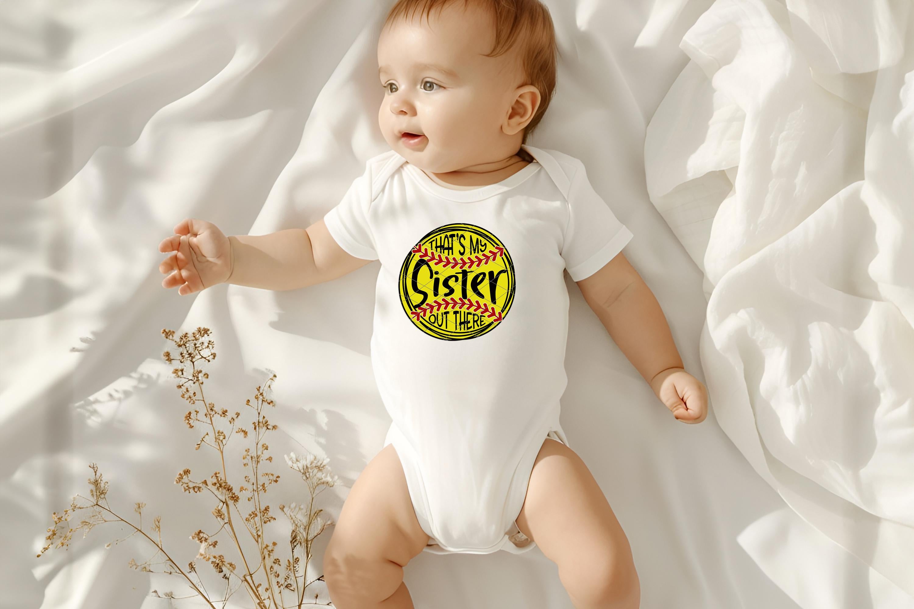 A lifestyle photo of a baby wearing a white baby onesie with a yellow softball graphic that says 'That's my sister out there'.