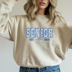 Natural/Sand sweatshirt with "Senior Est. 2025" floral design, styled casually with jeans.