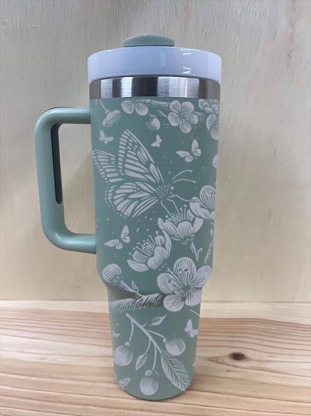 Laser engraved cherry blossom tumbler with white lid and handle, sage green color