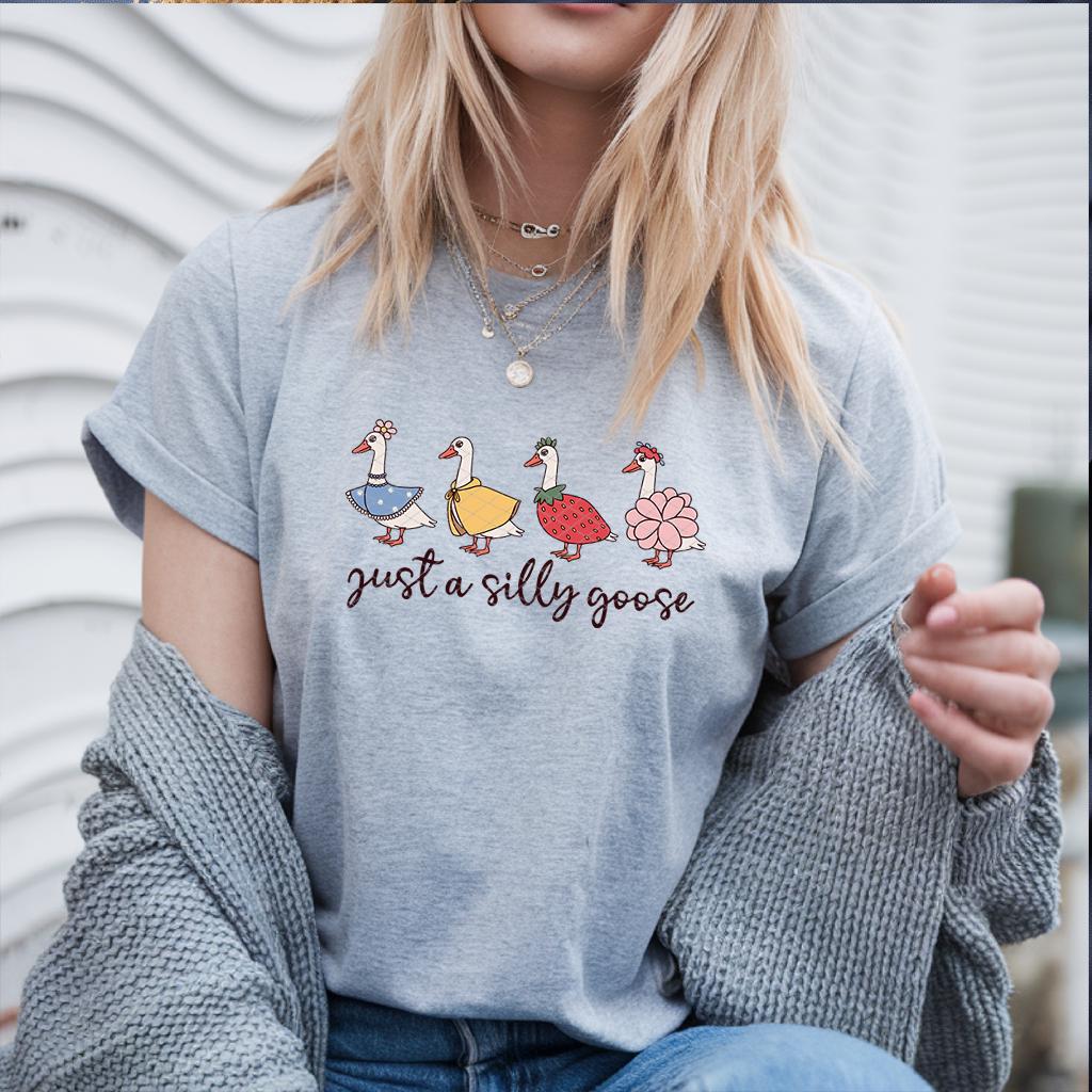 Blonde woman wearing heather grey goose shirt with cardigan and layered necklaces