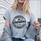 Grey t-shirt with black "Promoted to Grandma" print worn by woman outdoors.