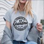 Grey t-shirt with black "Promoted to Grandma" print worn by woman outdoors.