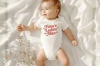 Baby lying on white blanket wearing "Future Ladies' Man" onesie with soft lighting