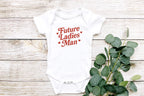 Close-up flat lay of onesie styled with eucalyptus leaves on light wood background