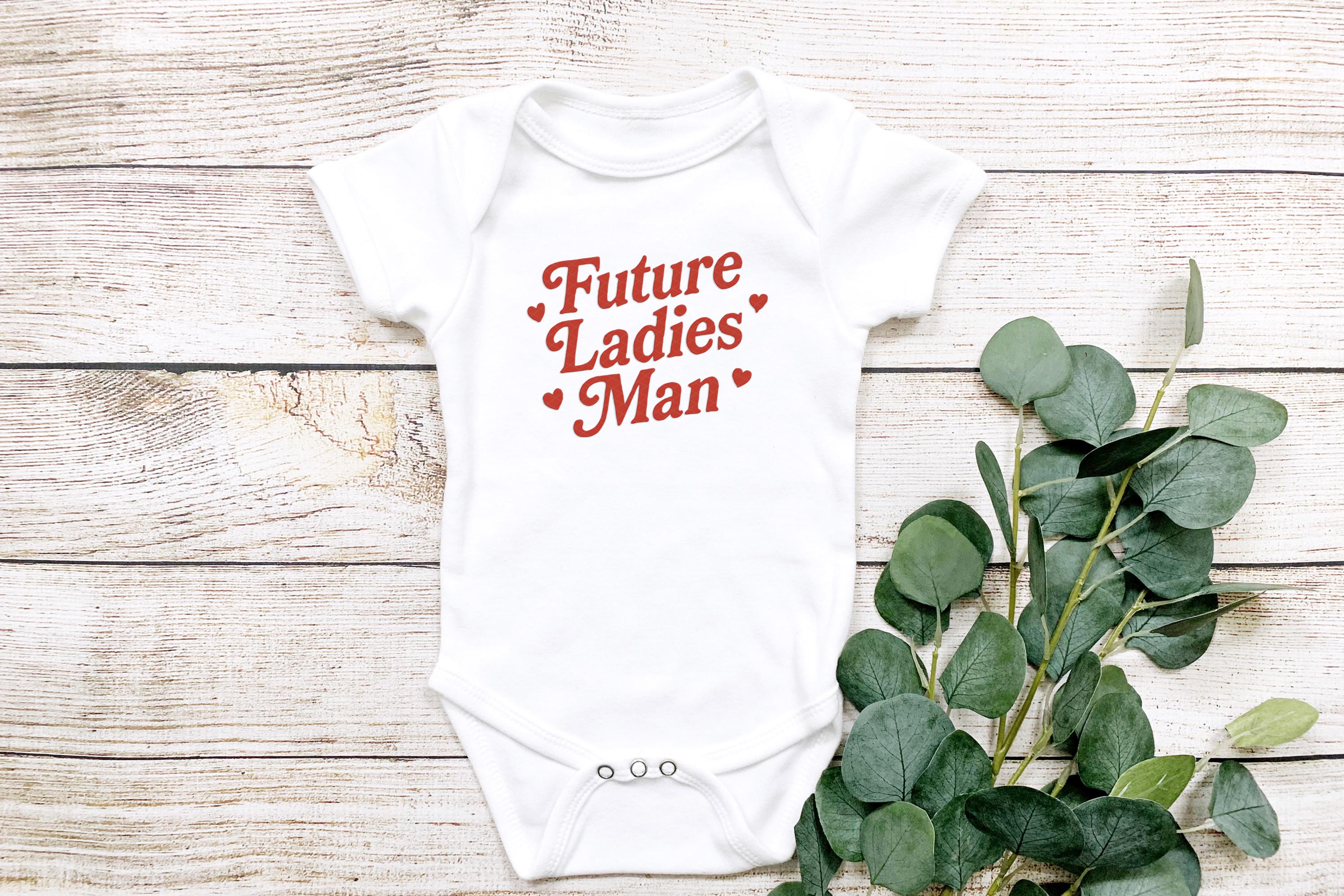 Close-up flat lay of onesie styled with eucalyptus leaves on light wood background
