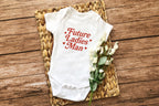 Flat lay of "Future Ladies' Man" onesie with woven basket and flowers
