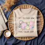 Folded natural sweatshirt displayed on a wicker tray with "Can't Talk Right Now Doing Teacher Stuff" graphic.