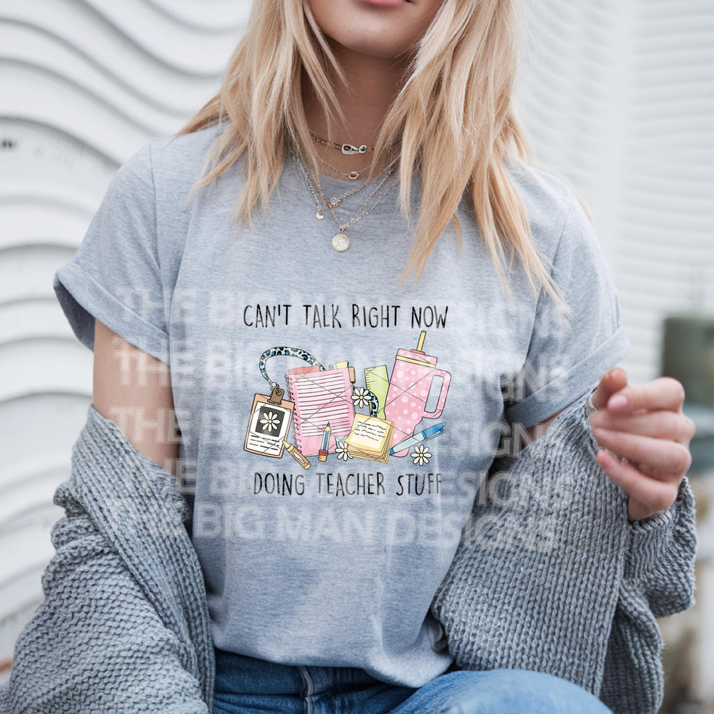 Woman wearing a grey t-shirt styled casually, featuring the "Can't Talk Right Now Doing Teacher Stuff" design.