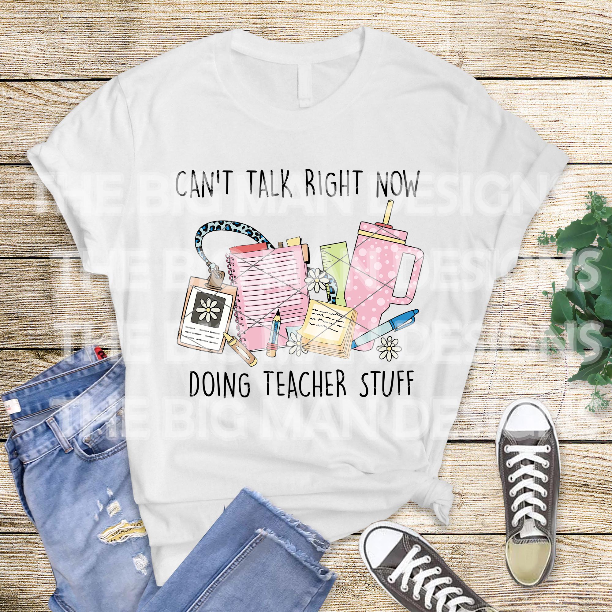 White t-shirt flat lay with jeans and sneakers, featuring "Can't Talk Right Now Doing Teacher Stuff" teacher graphic.