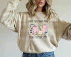 Woman wearing a natural-colored sweatshirt with "Can't Talk Right Now Doing Teacher Stuff" design featuring teacher accessories.