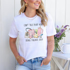Smiling woman modeling a white t-shirt outdoors, featuring the colorful "Can't Talk Right Now Doing Teacher Stuff" design.