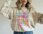 Woman wearing a natural sweatshirt with "Teaching is a Work of Heart" colorful pencil and floral design.