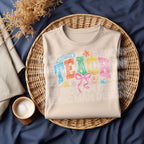 Natural sweatshirt folded in a basket, displaying colorful "TEACH" design.