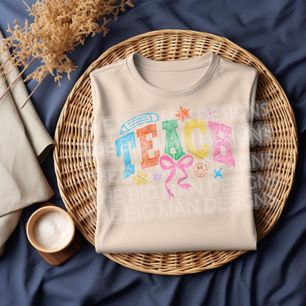 Natural sweatshirt folded in a basket, displaying colorful "TEACH" design.