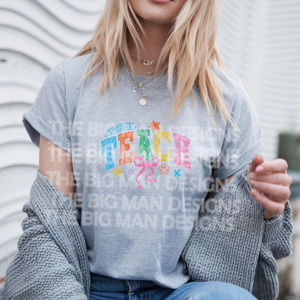Woman in grey T-shirt with "TEACH" colorful graphic and casual outfit.