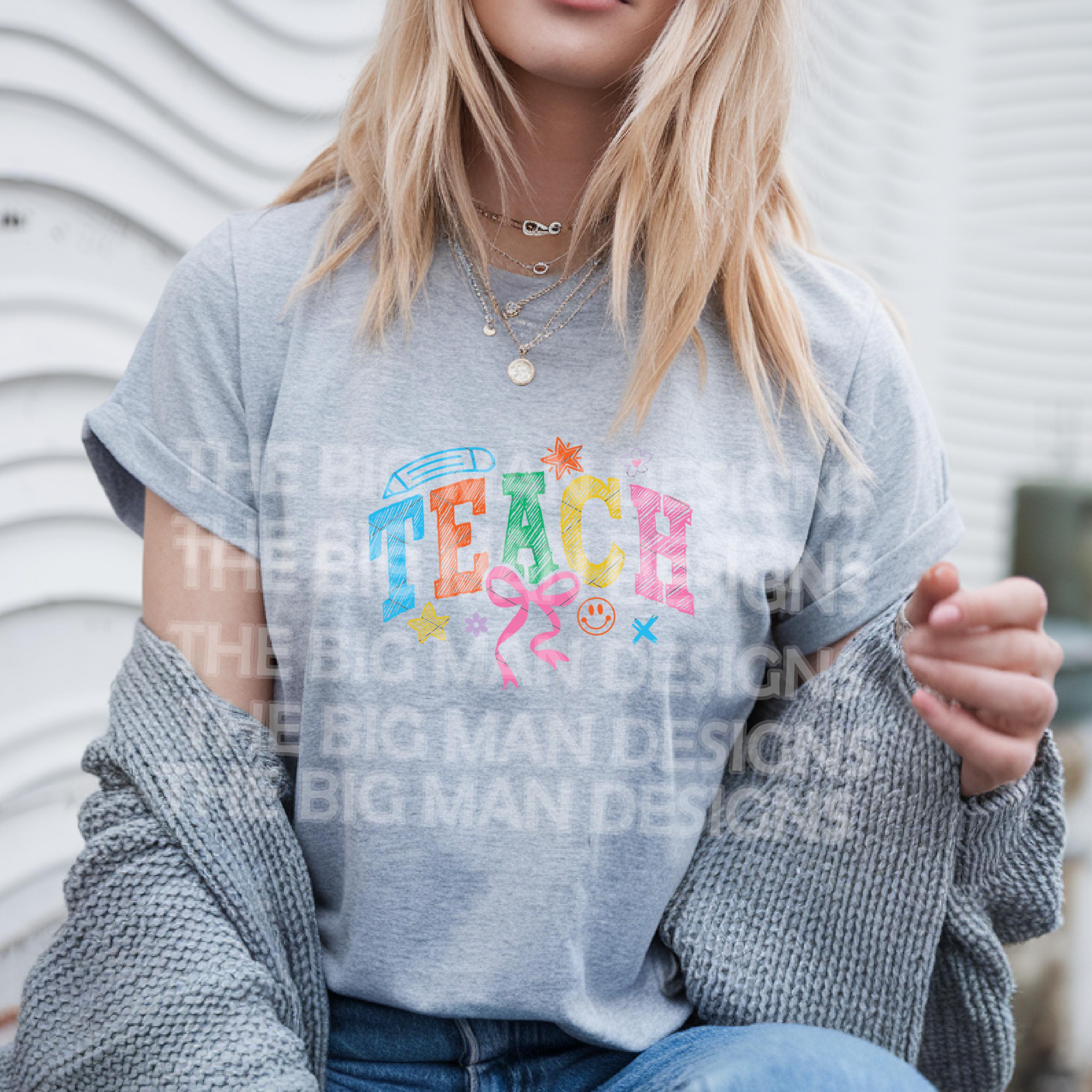 Woman in grey T-shirt with "TEACH" colorful graphic and casual outfit.