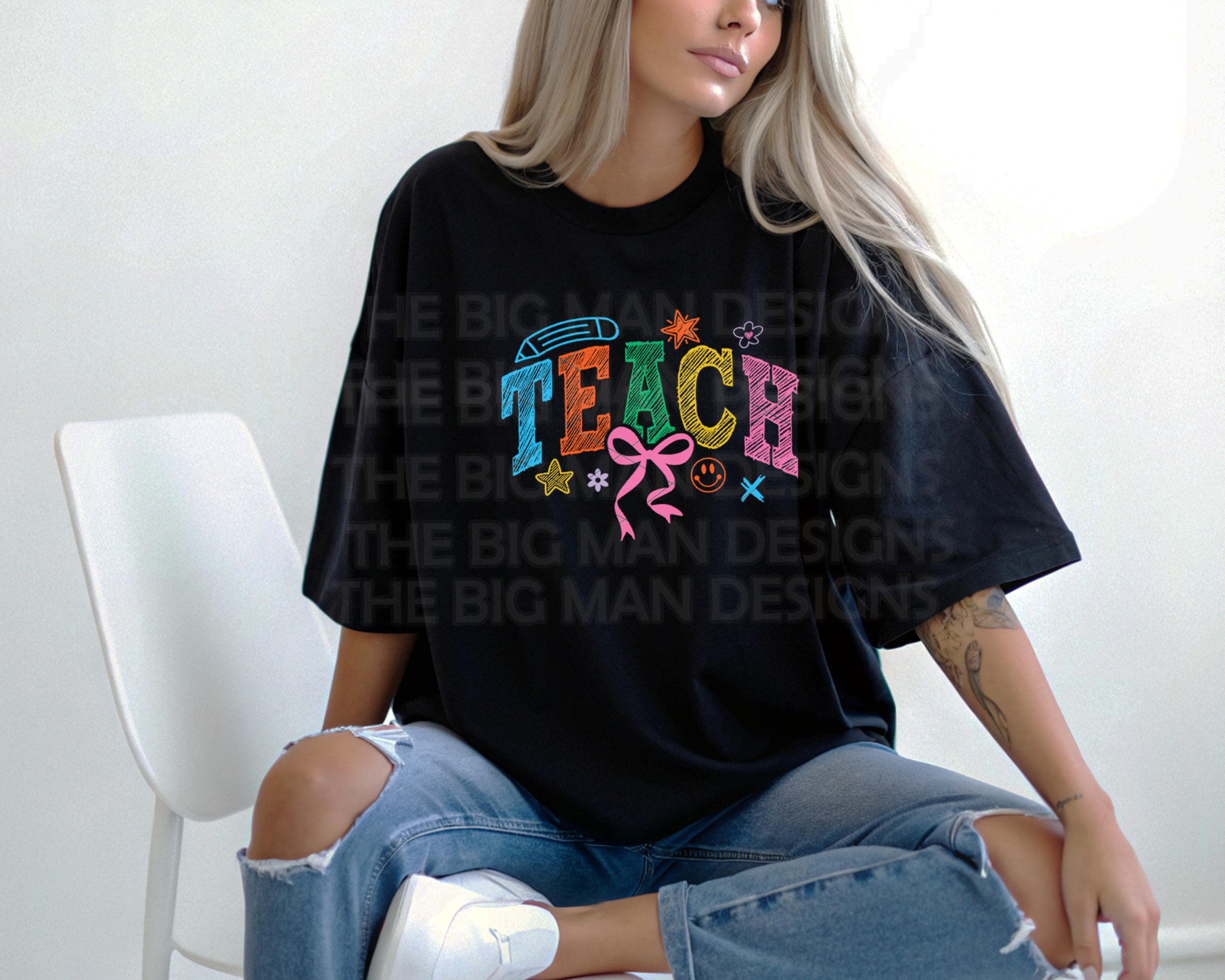 Woman sitting cross-legged in a black oversized T-shirt with colorful "TEACH" graphic.