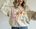 Woman wearing natural sweatshirt with vibrant school supplies and "Teach Love Inspire" text.