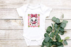 Flatlay baby onesie with duck design and eucalyptus greenery.