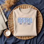 Natural/Sand sweatshirt with "Senior Est. 2025" floral design, styled casually with jeans.