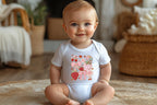 Baby wearing strawberry and bow printed onesie, sitting on cozy rug with wicker decor.