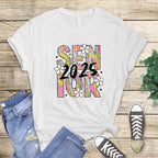 Flat lay of white Brushstroke Senior 2025 T-shirt paired with ripped jeans and sneakers on rustic wood background.