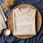 Beige shirt with "Promoted to Grandma, Est. 2025, Best Grandma Ever" design on woven basket.