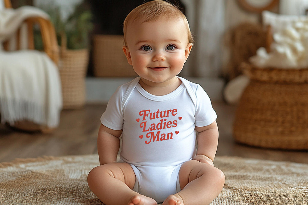 Baby boy sitting up smiling in white onesie with "Future Ladies' Man" text