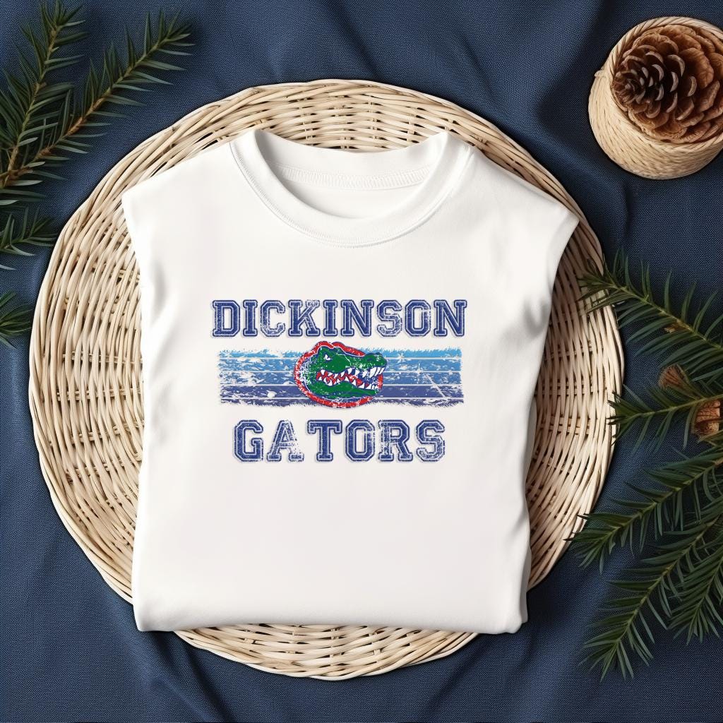 Folded Dickinson Gators white shirt on woven basket with pinecones