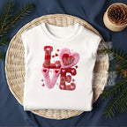 White shirt flat lay showing plush chenille LOVE heart Valentine heat transfer design with greenery