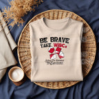 Be Brave Take WISCs on a cream color flat lay mock up tshirt