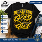 A black short-sleeve graphic T-shirt laid flat with jeans, a shoe, and decorative props around it. The shirt features large yellow and gold text reading 'DICKINSON GATORS GOLD OUT GO GATORS!' with a gator illustration.